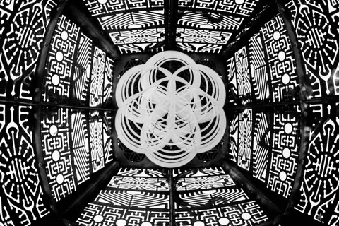 Intricate geometric patterns create a mesmerizing optical illusion within a dark, symmetrical structure.