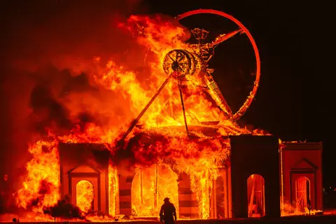 The Man burns brightly against a dark sky, silhouetted by intense flames and smoke.